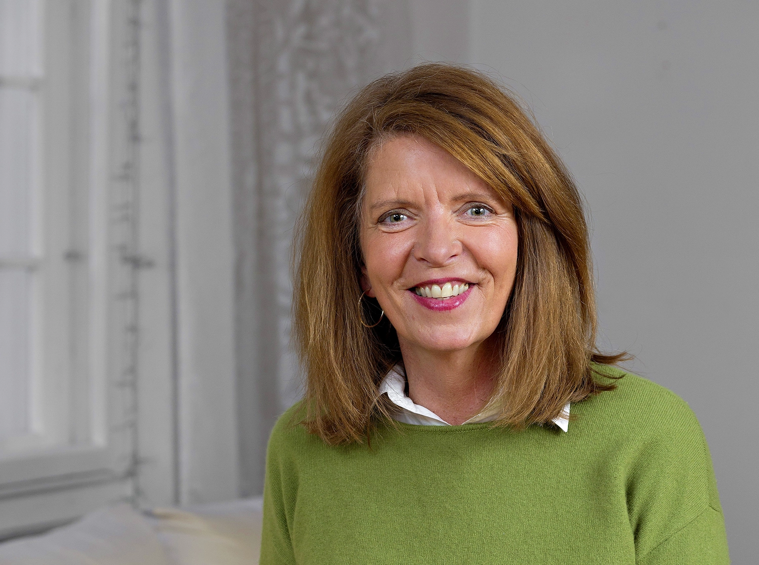 Gabriele Aumeier lächelt in einem hellen Raum, trägt einen grünen Pullover.
